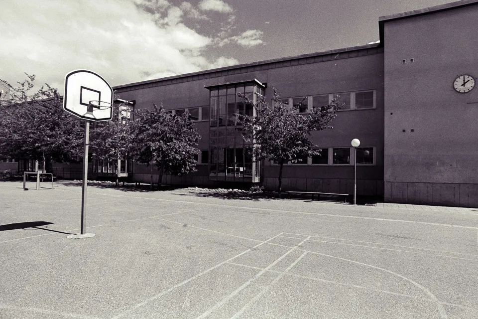 Low-saturation image of a concrete schoolyard with basketball hoop